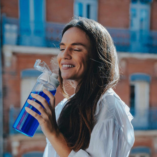 Femme buvant une gourde de phycocyanine