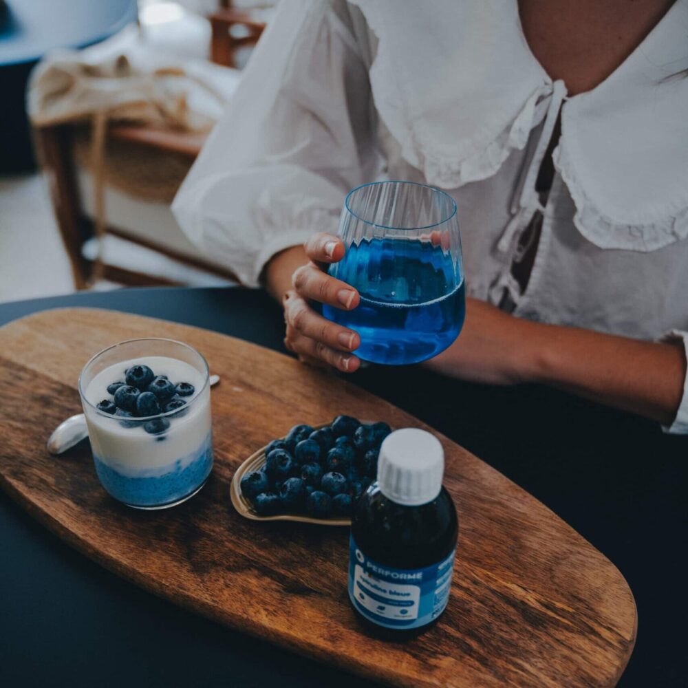 Femme buvant un verre de phycocyanine 2000mg/l pendant le petit déjeuner